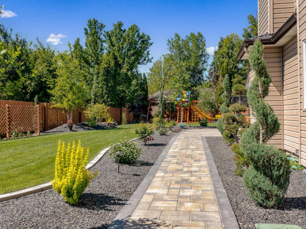 Paver walkway through a landscaped yard